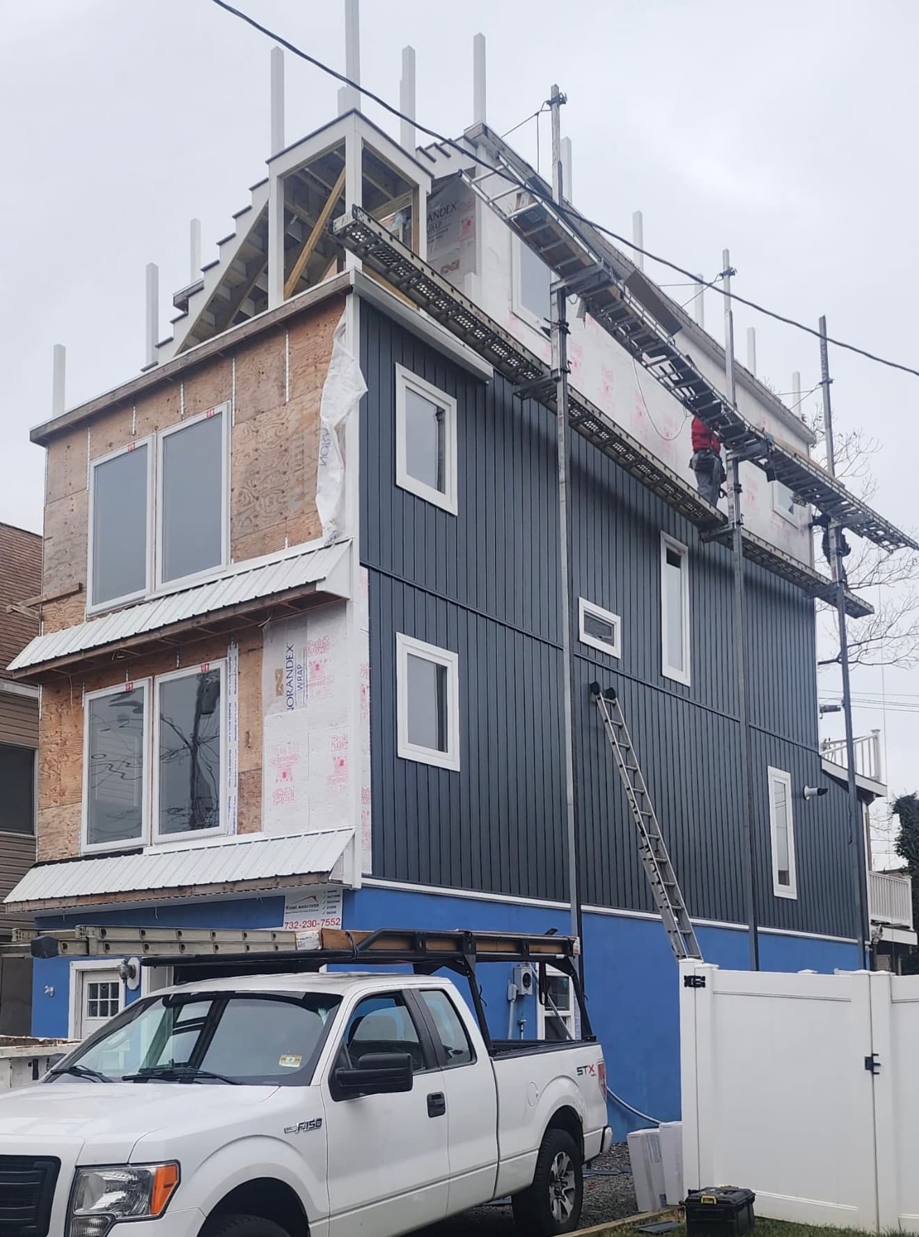 Blue siding installation with scaffolding on residential building